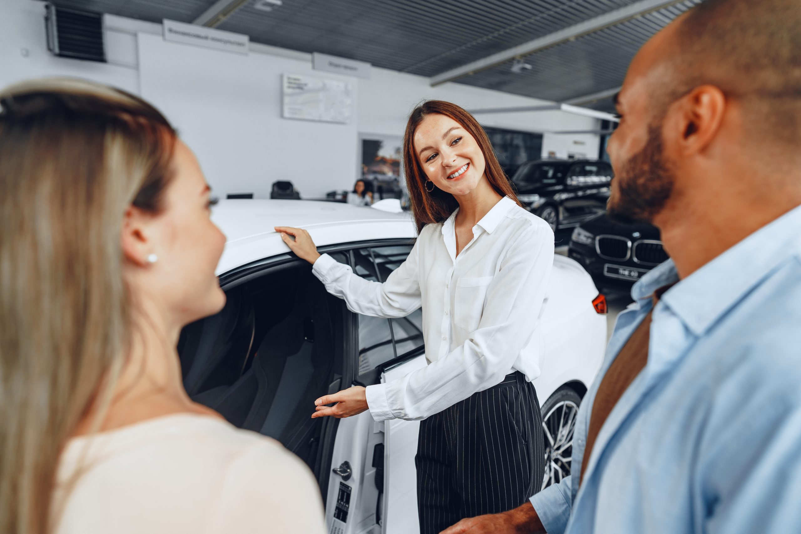 Woman car dealer explaining to buyers features of their new car